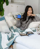 woman sitting on beige sofa with coffee cup next to interlock throw pillow in oxford tan by Anchal