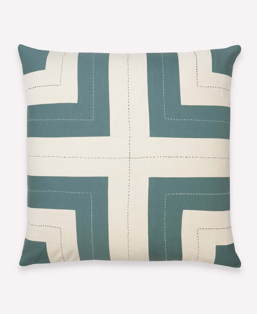 Cream and teal throw pillow with cross design in middle