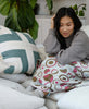 woman on beige sofa with spruce green interlock throw pillow by Anchal Project