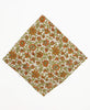 Cream colored bandana with a full orange and olive green floral pattern
