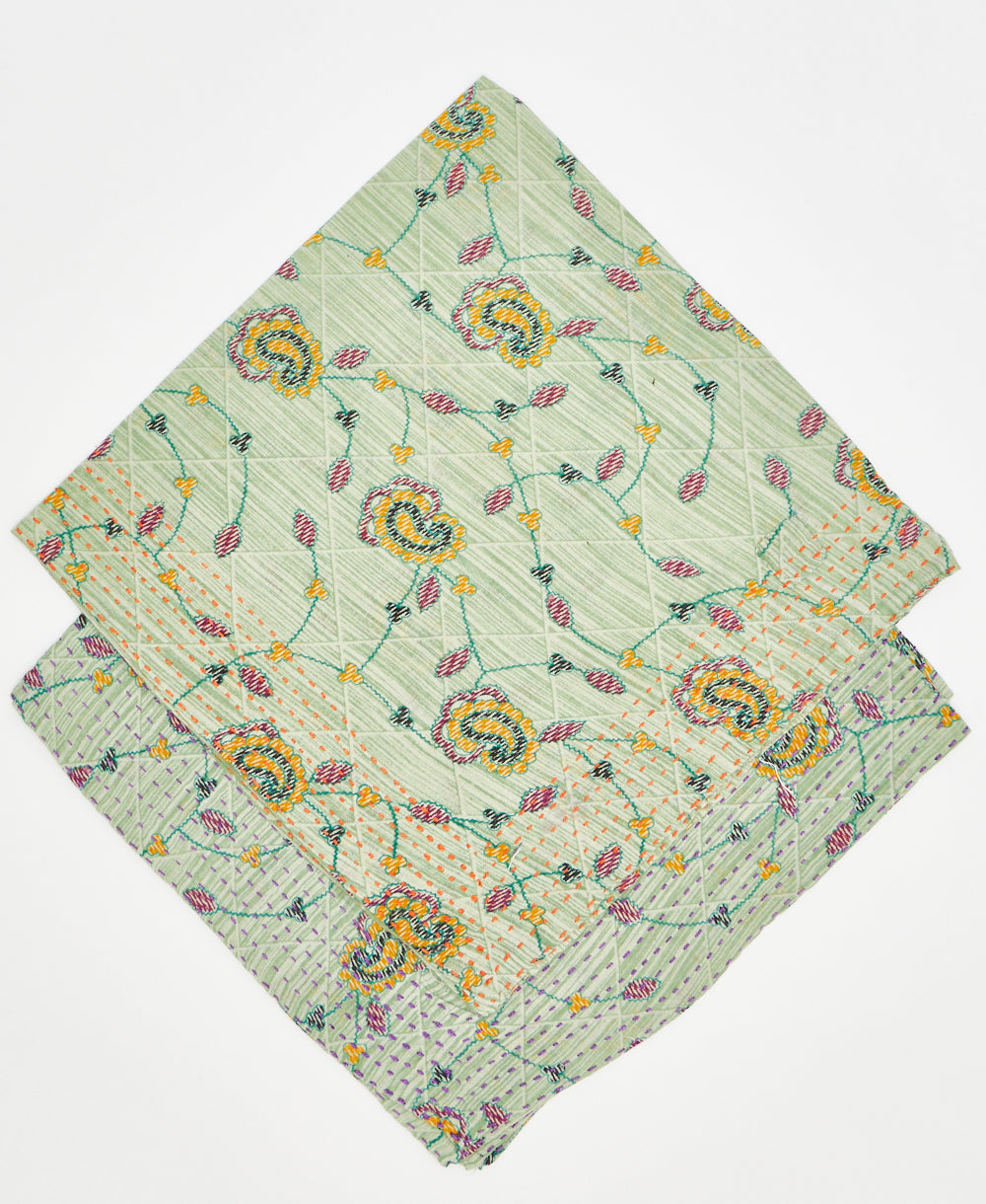 two green floral bandanas stacked on each other to show their different thread colors. one as orange kantha stitching along its edges while the other has purple kantha stitching 