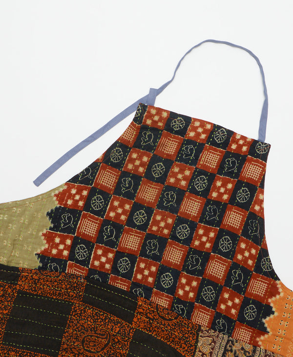 Brown and black checkered print apron with orange and green details featuring three large pockets  