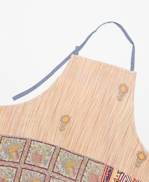 Muted red line print apron with a minimal floral pattern and three large pockets featuring a contrasting pattern. 