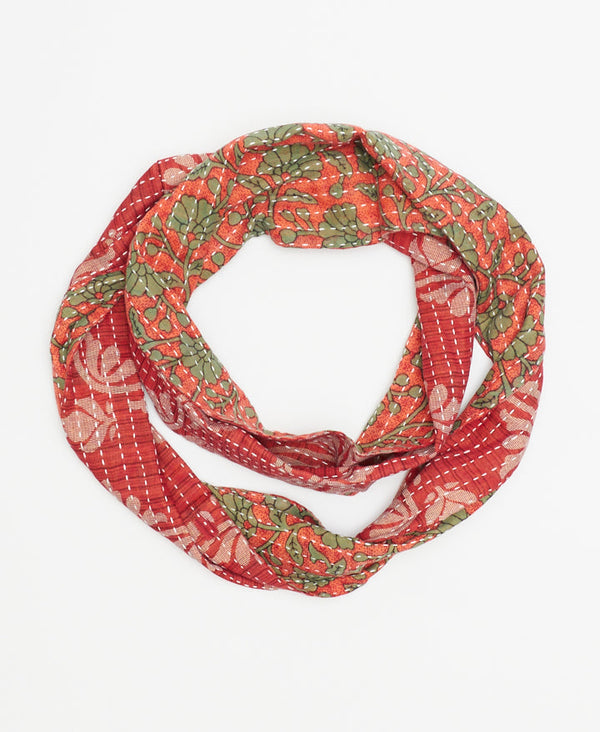 red, white and green hand-stitched infinity scarf featuring a tag with the signature of the woman artisan who made the scarf