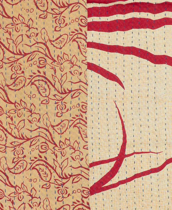 one side of the infinity scarf features red swirling vines on a dark beige background while the other side features bold graphic red lines on a pale beige background