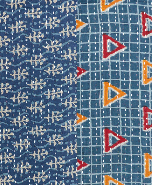this fair-trade infinity scarf features red and orange triangles on a ocean blue background with a white grid on one side and pale blue waves and white seaweed pattern on the other side
