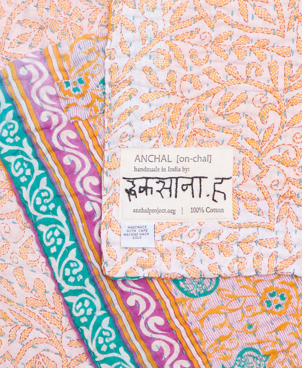 Tag featuring the hand-stitched signature of the maker 