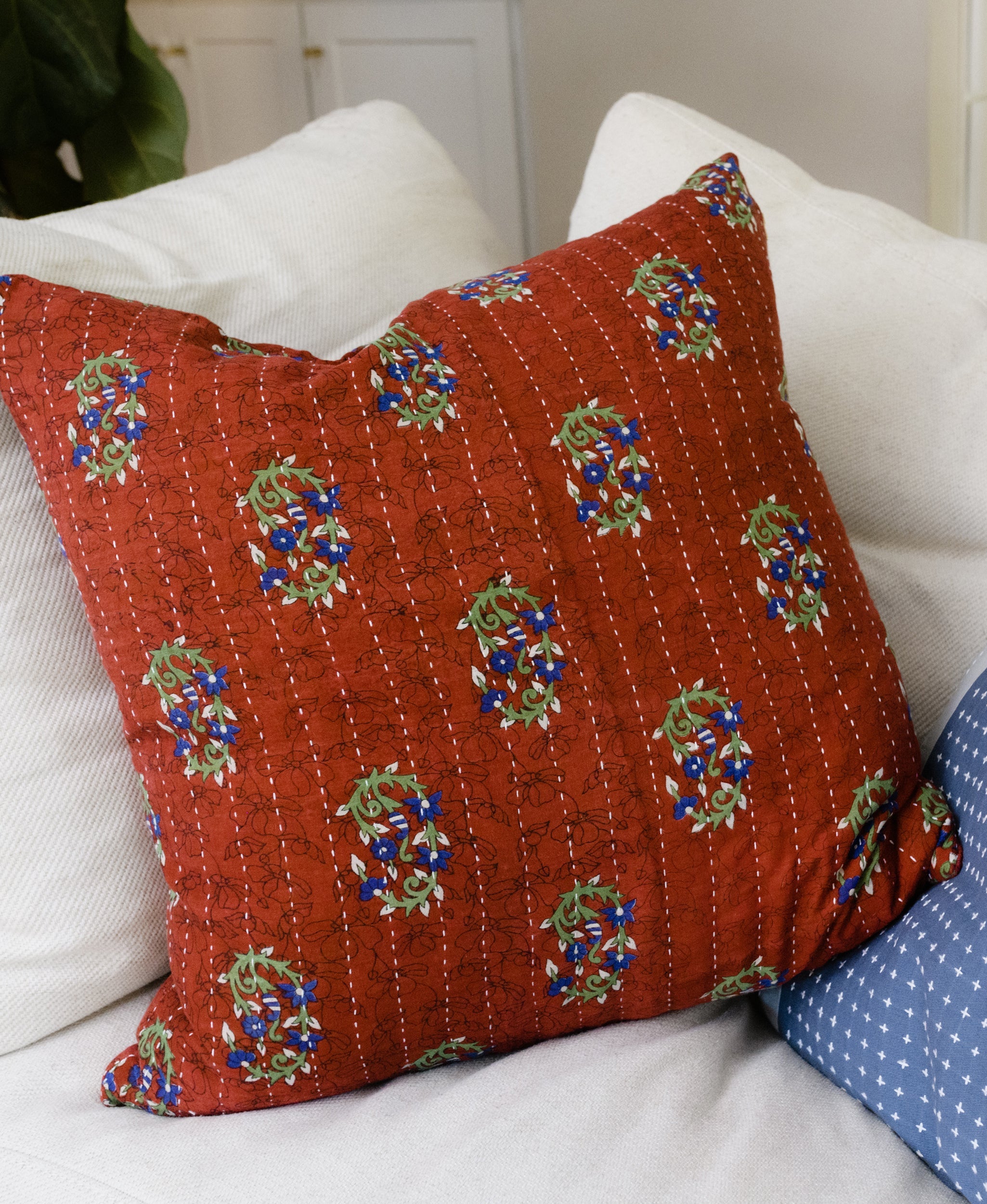 red anchal vintage kantha throw pillow on a white couch