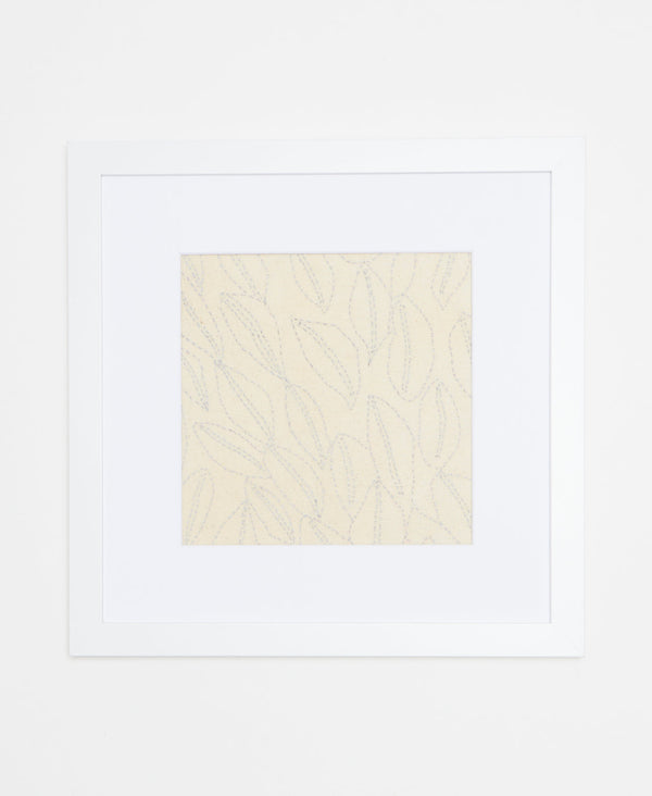 Handcrafted artisan-made textile art featuring light blue sitching that forms a leaf pattern 