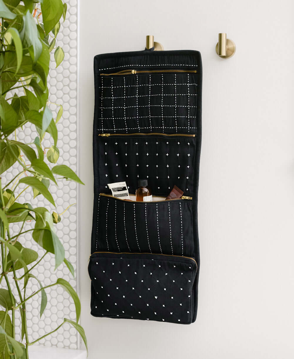 black hanging toiletry travel bag hanging on silver hook in bathroom