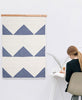 geometric modern quilt hung on wall with wooden quilt hanger