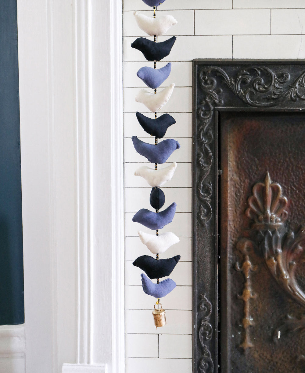 Monochromatic bell tota in black, blue and white hanging against white tiled fireplace