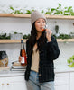 woman wearing modern quilted jacket with grid-stitch embroidery drinking a glass of rose in modern kitchen