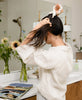 woman putting her hair in high ponytail with organic cotton kantha embroidered white scrunchie by Anchal Project