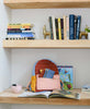 small colorblock backpack on bookshelf with books