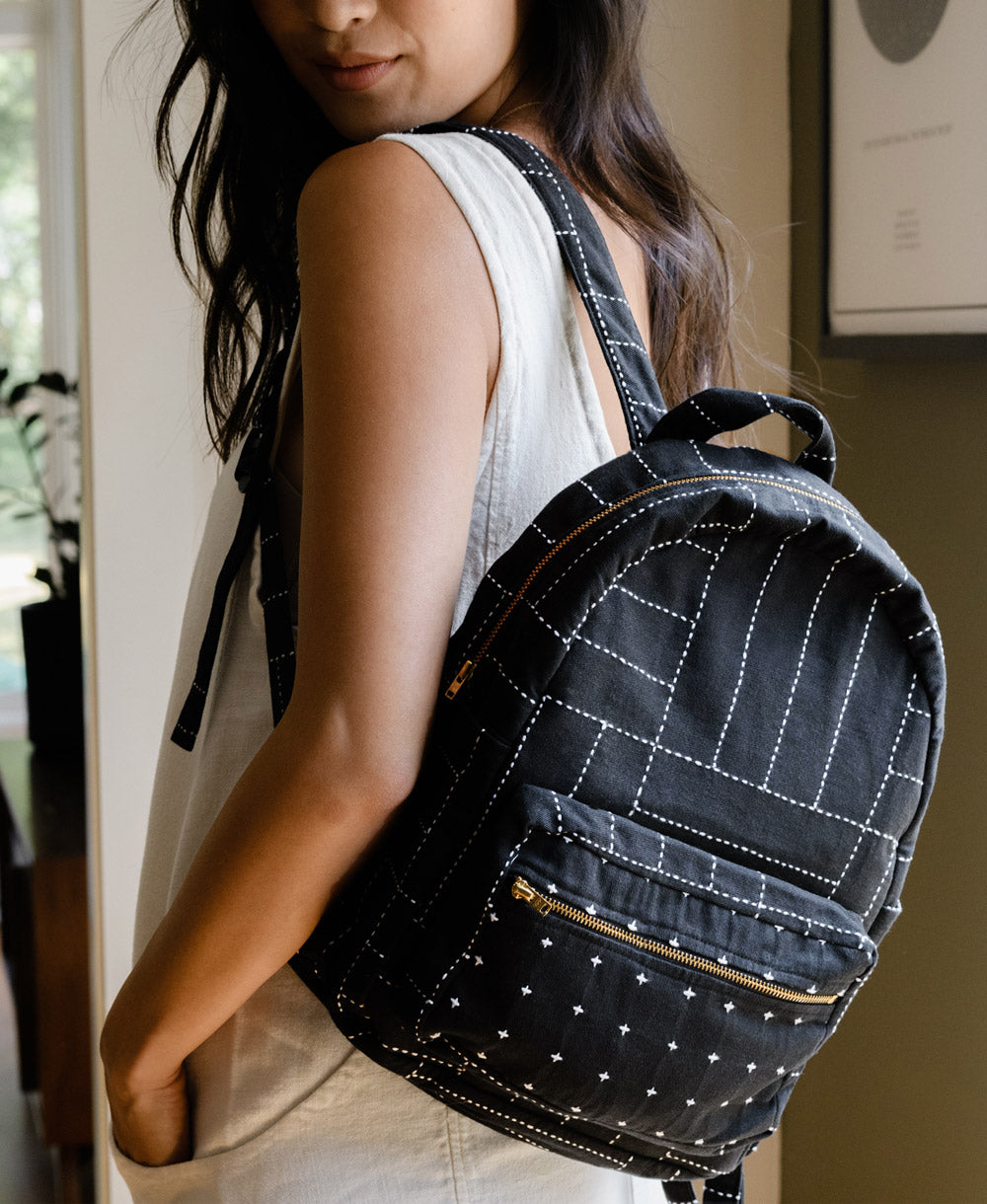 Woman looking back at camera wearing black crosshatch pillow with small white cross design