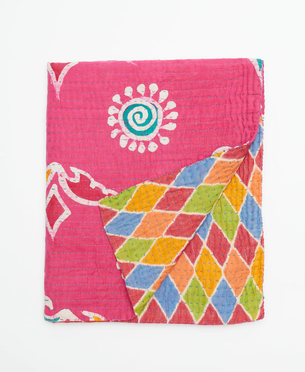 Bright and vibrant pink small cotton quilt that is crafted from layers of recycled fabrics 
