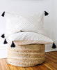 embroidered organic throw pillow with tassels on woven pouf