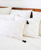 minimalist all white bedroom pillow arrangement featuring hand-embroidered throw pillows