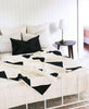 Triangle quilt throw styled in modern minimalist bedroom that pairs perfectly with Anchal Project pillows and throws