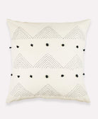 Embroidered throw pillow in natural white with black pom poms