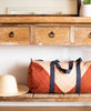 modern colorblock barrel shaped duffel bag sitting on natural wooden entryway table